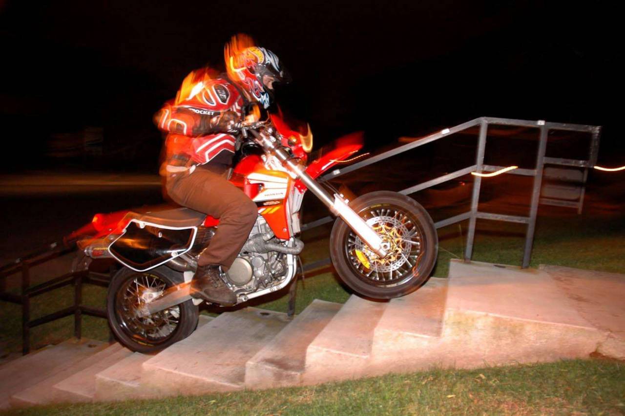 Supermoto motorcycle climbing stairs night long exposure flash