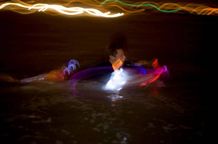 Surfing nightsurfing glow stick paddle out
